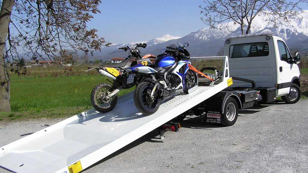Du motociklai stovi užfiksuoti ant nuleistos tralo platformos
